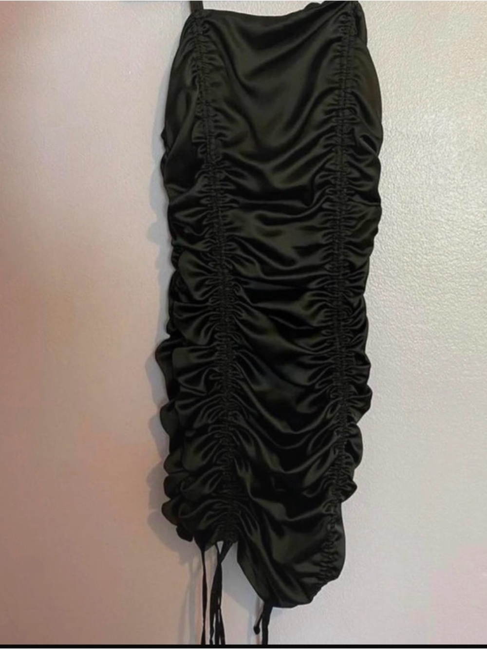 Black ruched mini dress with adjustable drawstrings at the bottom.